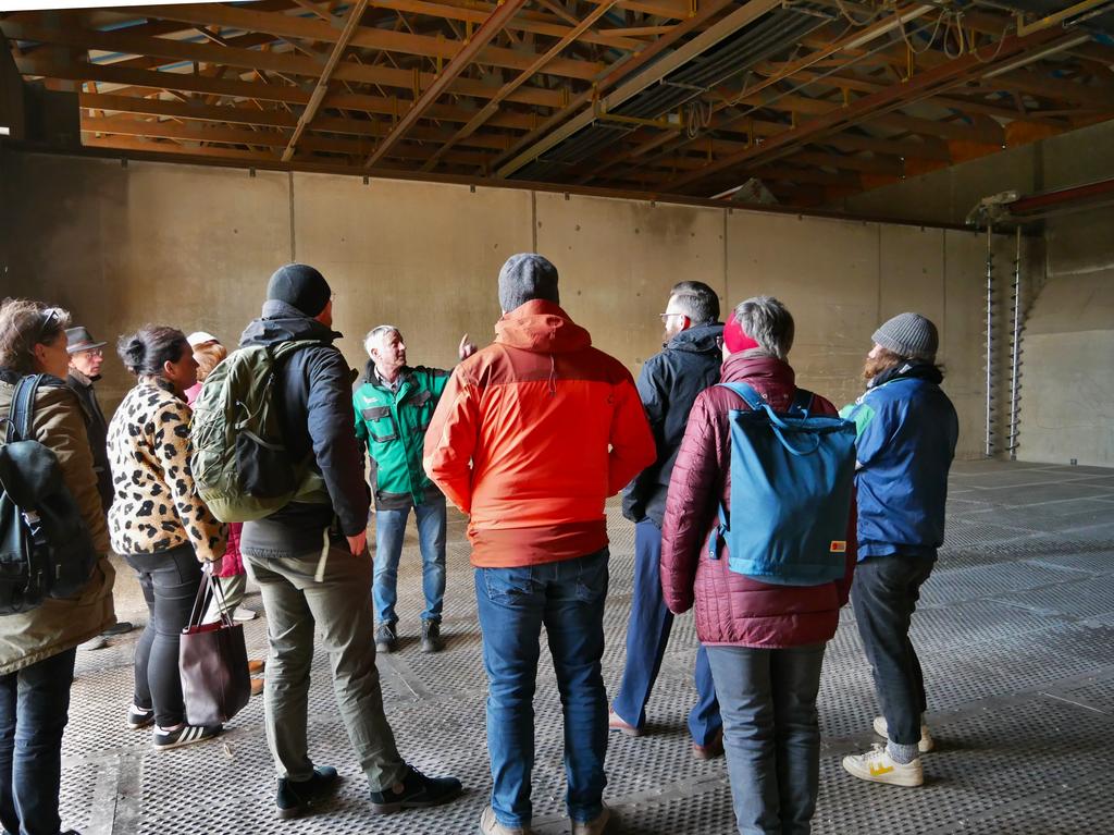 Eine Gruppe Menschen besichtigt eine Lagerhalle.