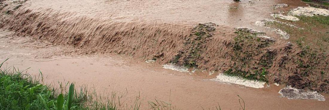 Wasser spült Erde einen Hang hinab in einen Graben