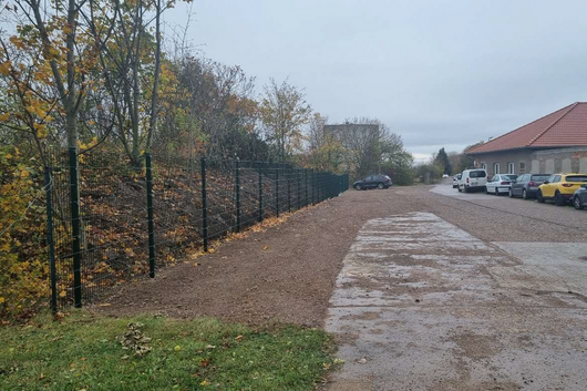 eine freie Fläche neben einer Straße, auf der anderen Seite parken Fahrzeuge