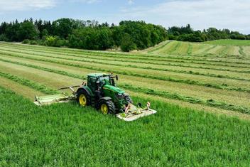Traktor auf Wiese mäht Klee