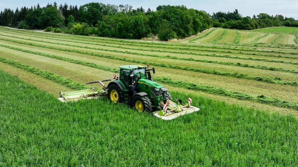 Traktor auf dem Feld erntet Klee
