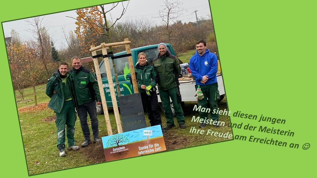 Personengruppe steht neben einem frisch gepflanzten Baum im Gelände des LVG