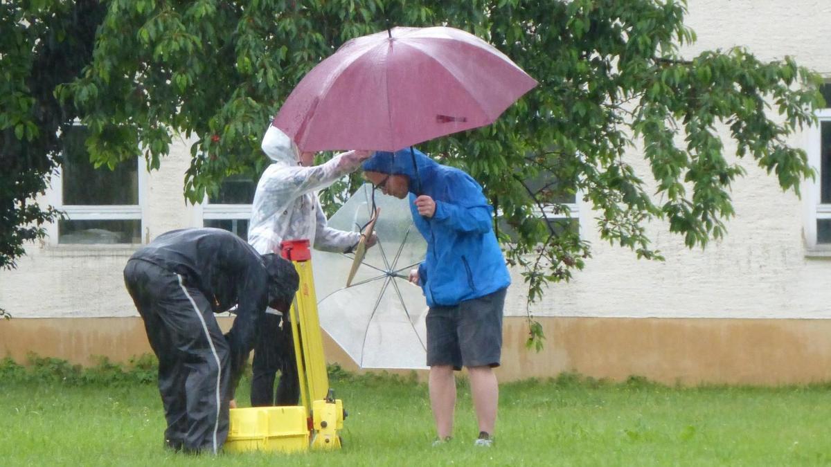 Fachschüler bei Vermessung im Regen mit Schirm