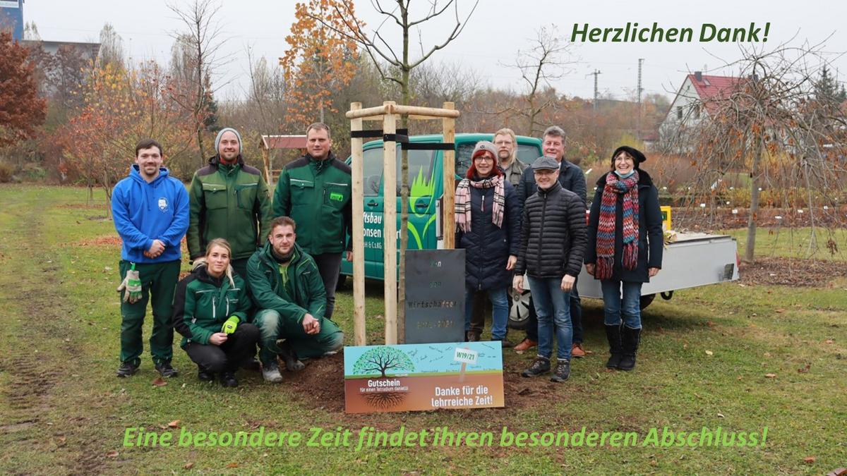Gruppenbild von Personen neben einem neu gepflanzten Baum